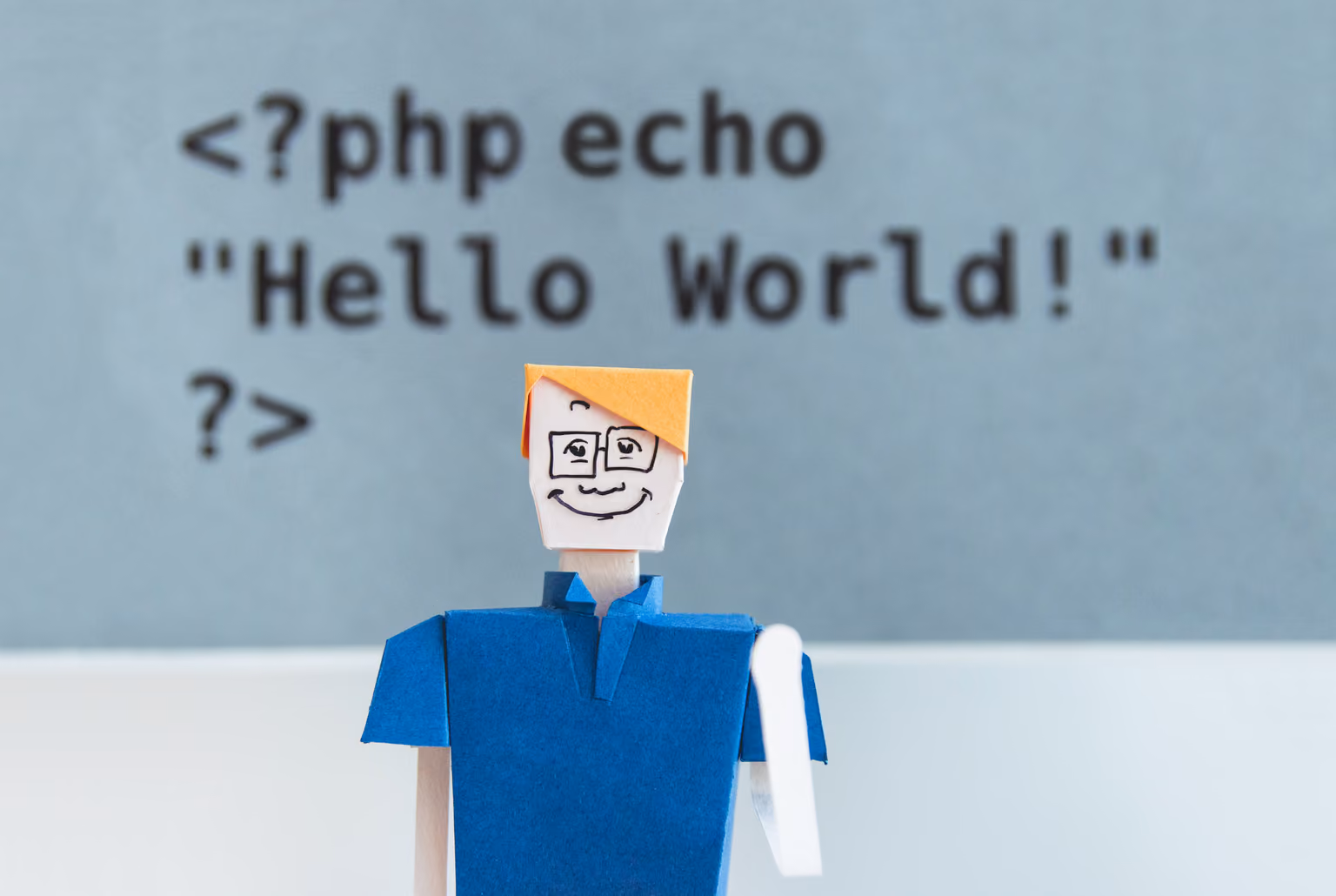 Бумажная фигурка на фоне кода Hello World на PHP